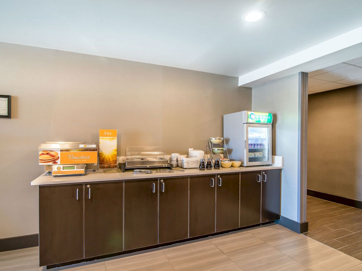 A small breakfast area with a counter, coffee machine, cereal dispenser, juice machine, toaster, and bread items.